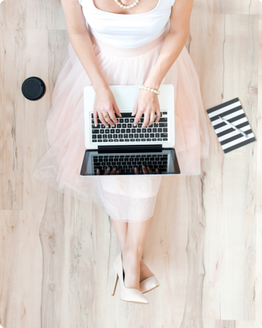 woman in pink skirt sitting on the floor with coffee and a notebook, for the blog post Learn the new rules of blogging in 2025 and why less content can create more impact.