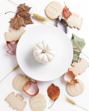 Flat lay with pumpkins, fall leaves, and cookies beside a keyboard—cozy workspace for writing gratitude blog posts.