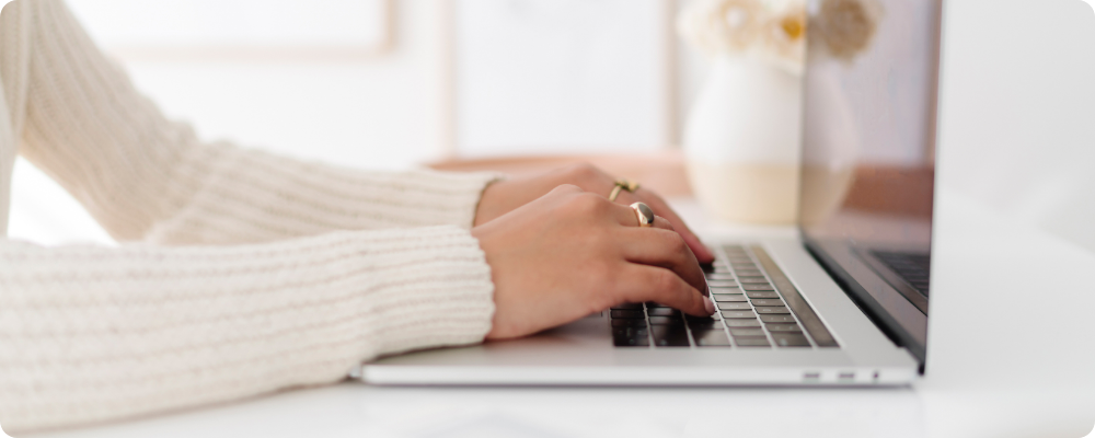 Close-up of introverted coach typing on laptop, writing a calm blog about her offer using quiet marketing.
