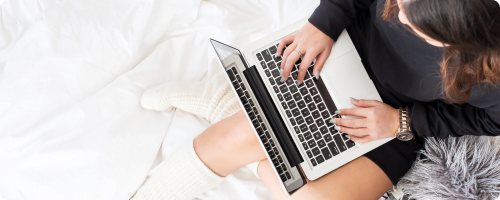 Introverted coach relaxing on the couch with laptop and cozy socks, doing a simple blog post review for her blogging strategy.