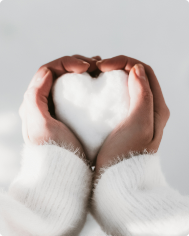 Close-up of hands forming a heart from snow, representing calm trust-based marketing for introverted solopreneurs.