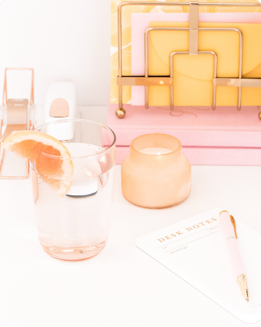Bright desk with citrus water, candle, notes and pen—simple blog tools for sorting blog ideas on your blog page.