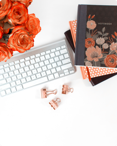 Workspace with keyboard, floral journals, and roses, showing how journaling for business blogging supports clear writing ideas.