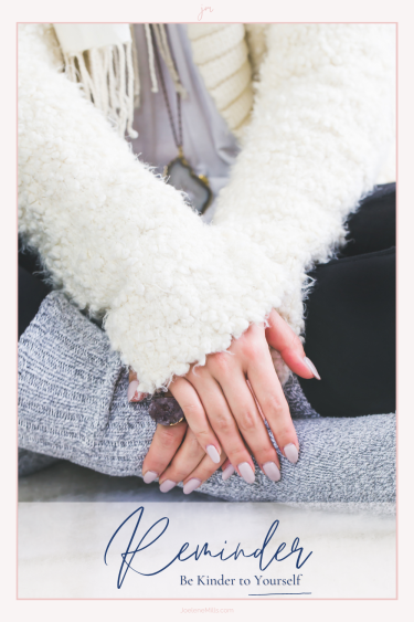 Close up of woman's hands on her lap with the words "reminder be kinder to yourself"