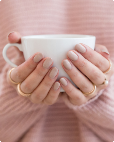 Hands holding a white mug in a pink sweater, symbolizing calm consistency and trust on your blog.