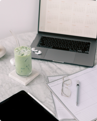 Iced drink beside a laptop and planner, a calm setup for quiet blogging and new blog post ideas.