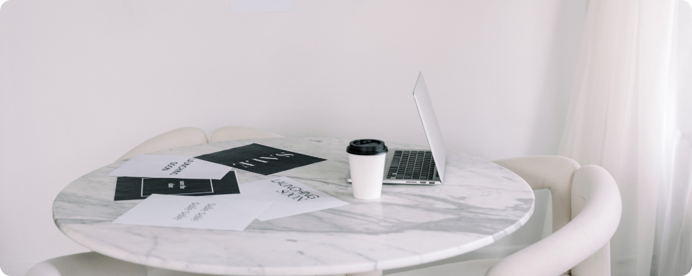 Marble desk with open laptop, coffee cup, and sale flyers, representing calm planning for a quiet Black Friday blog strategy.