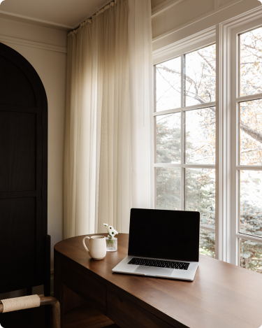 Laptop and coffee on sunny desk by window, calm blogging workspace for a quiet marketing blog post.