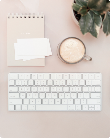 Minimal desk setup with keyboard, notebook, and coffee, symbolizing consistency without overload in business content.