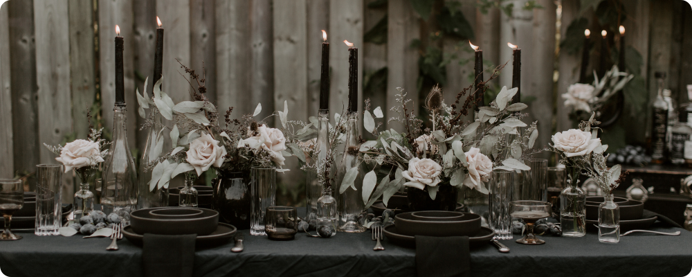 Elegant dark holiday tablescape with black candles, neutral roses, and moody décor—styled for quiet, seasonal blog or Pinterest content.