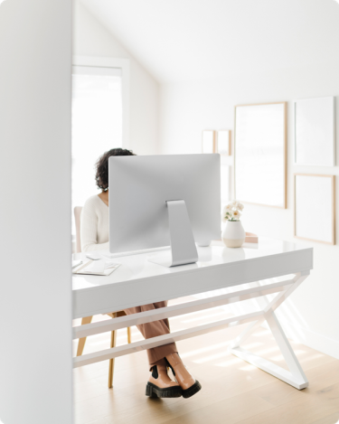 Woman entrepreneur working quietly at a bright desk, blogging about her offer without sounding salesy.