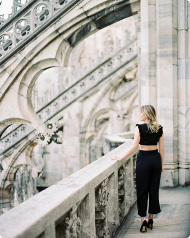 Woman standing on historic balcony looking ahead—symbolizing clarity, reflection, and the choice to live out of your imagination, not your history. With the words Let go of who you used to be