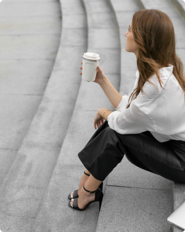 Introverted blogger sitting on city steps with coffee, taking a quiet break from social media and planning her next blog post ideas.