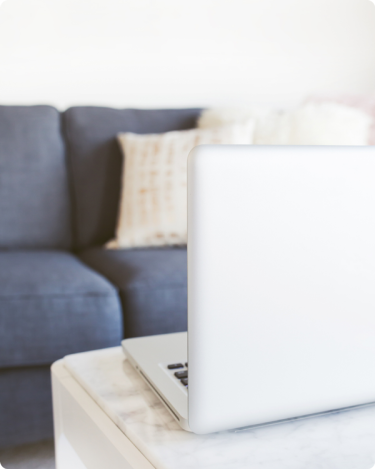 Minimal home workspace with laptop and cozy sofa, representing calm and organized blogging systems for coaches.