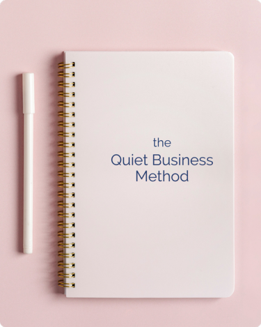 Spiral notebook on pink background with text "The Quiet Business Method"—framework for introverted entrepreneurs and quiet marketing.