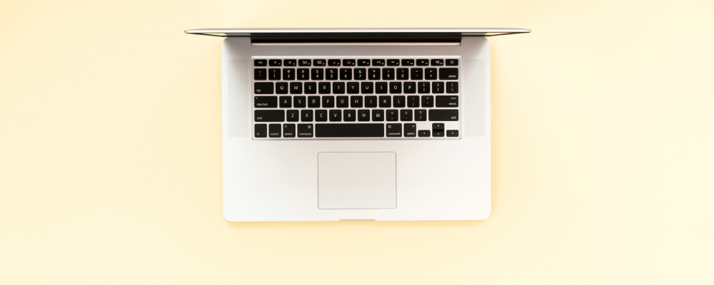 minimal laptop on yello desk symbolizing the new rules of blogging in 2025 for introverted coaches.
