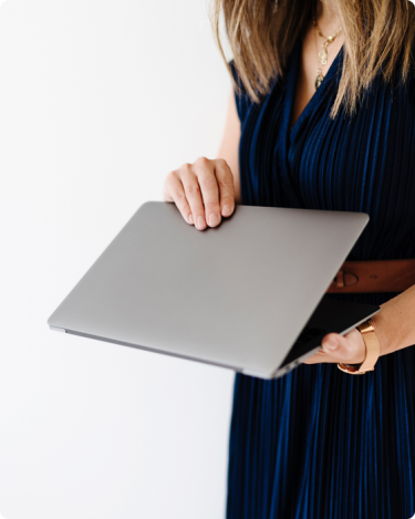 Woman in a navy dress holding a laptop, symbolizing calm focus and sustainable Blogging Consistency.