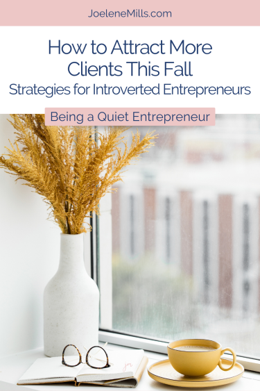 A coffee cup, notebook, glasses and vase with yellow plants on a windowsill with the words attract more clients as an introverted entrepreneur ths fall.